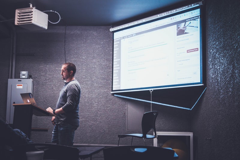Ein Bild von einerm Mann vor einer Leinwand mit PowerPoint Slides