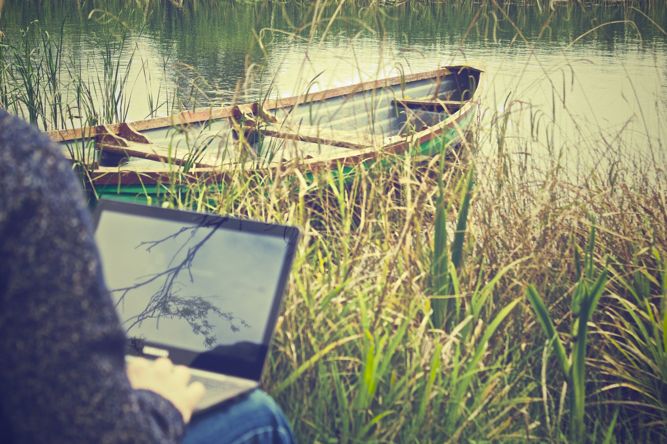 Ein Laptop an einem See mit einem Kanu im Hintergrund